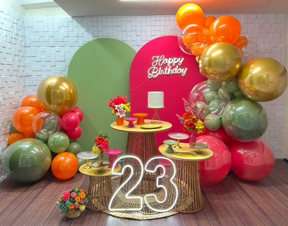 Decoração real da KA para aniversário de 23 anos, com painéis rosa e verde e balões coloridos